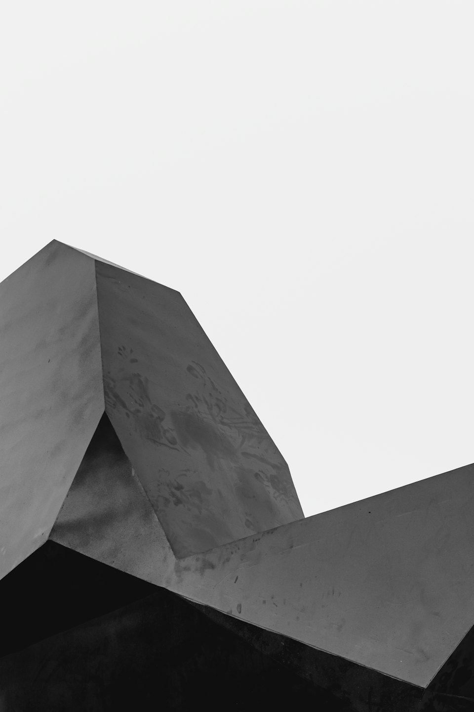 Dunkle, strukturierte geometrische Formen stehen auf Weiß.